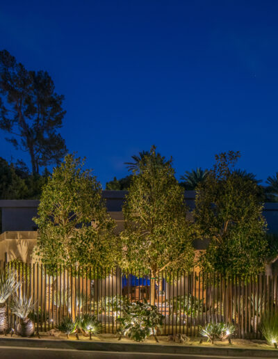 Modern house with artistic fence and garden illuminated at twilight.